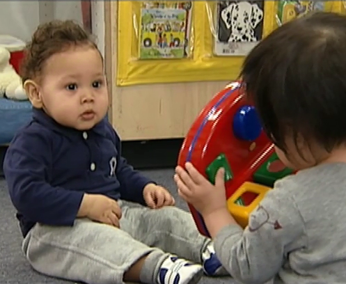 infant staring at toddler playing